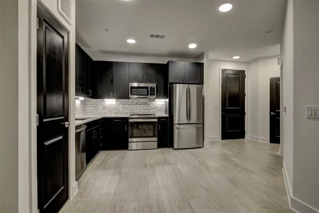 a large kitchen with stainless steel appliances granite countertop a refrigerator and a stove top oven