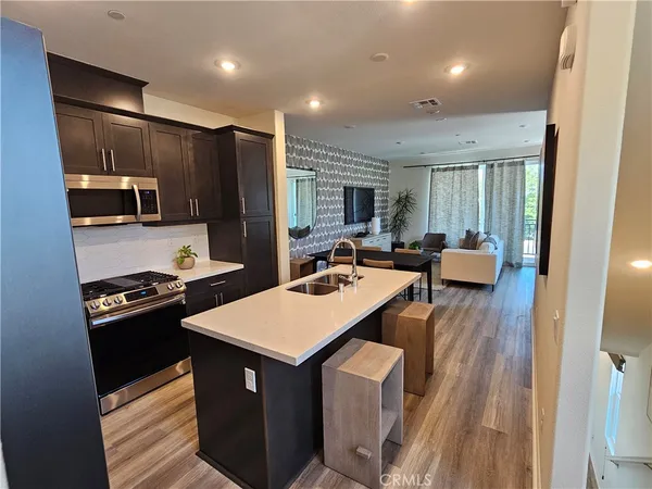 a kitchen with a refrigerator a stove top oven a sink dishwasher and wooden cabinets