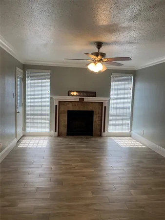 an empty room with windows fireplace and a chandelier fan