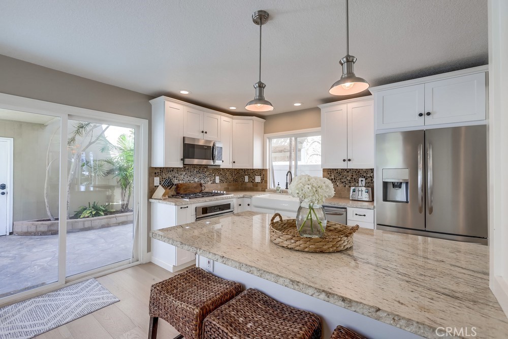 225 20th Street Huntington Beach, CA 92648 - Photo 13 of 47 a living room with stainless steel appliances granite countertop furniture a fireplace a flat screen tv and a window