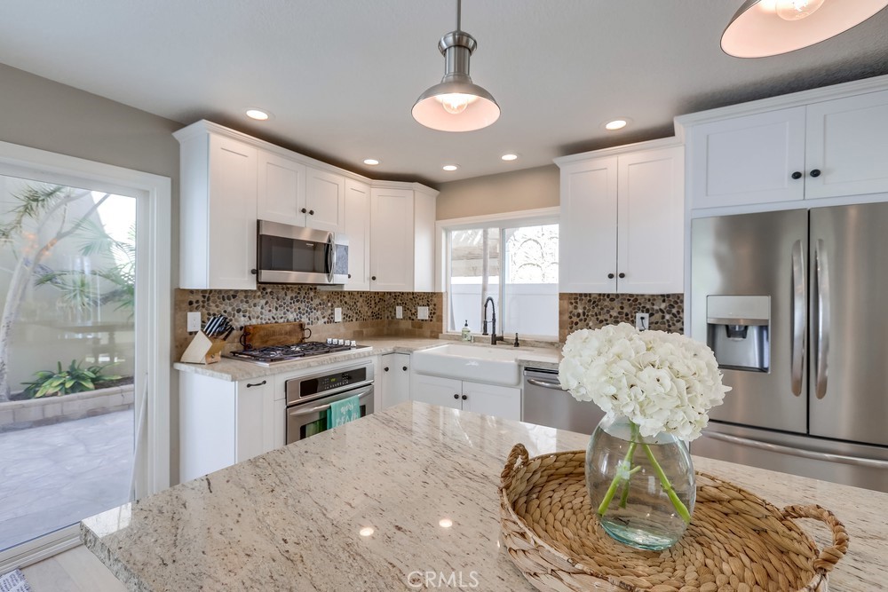 225 20th Street Huntington Beach, CA 92648 - Photo 5 of 47 a kitchen with stainless steel appliances granite countertop a stove refrigerator and cabinets
