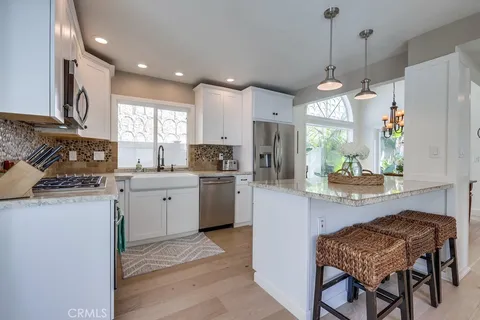 a kitchen with stainless steel appliances granite countertop a stove a sink a refrigerator a microwave oven with a dining table and chairs