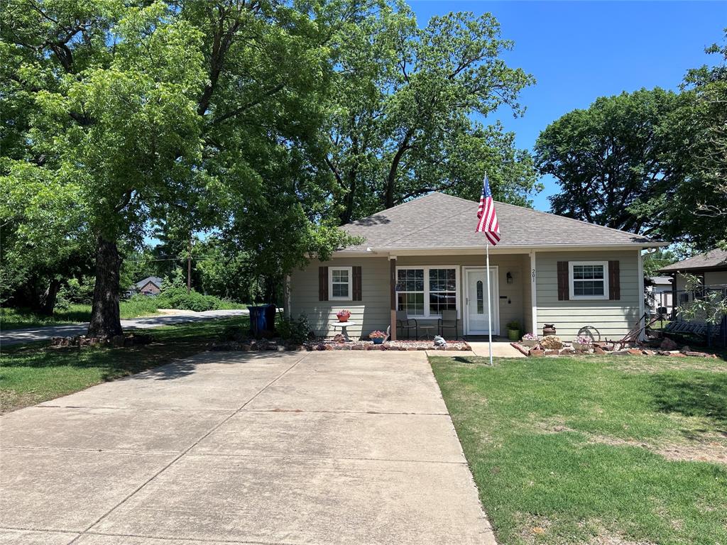 201 East Walker Street Denison, TX 75021 - Photo 1 of 19 a front view of a house with a garden and trees