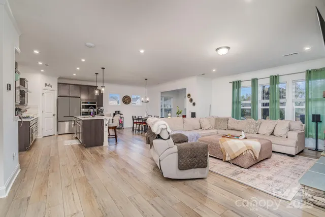 a living room with furniture kitchen view and a large window