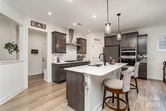 a kitchen with stainless steel appliances kitchen island granite countertop a sink refrigerator and cabinets