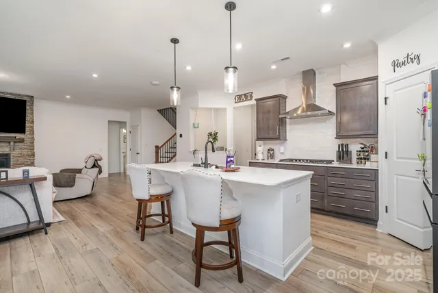 a kitchen with stainless steel appliances kitchen island granite countertop a table chairs refrigerator and microwave