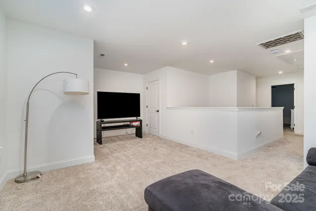 a view of an empty room with kitchen and a window