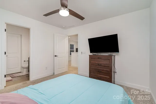 a bedroom with a bed and a flat tv screen on dresser