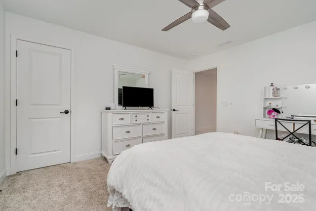a bedroom with a bed and a flat tv screen on dresser