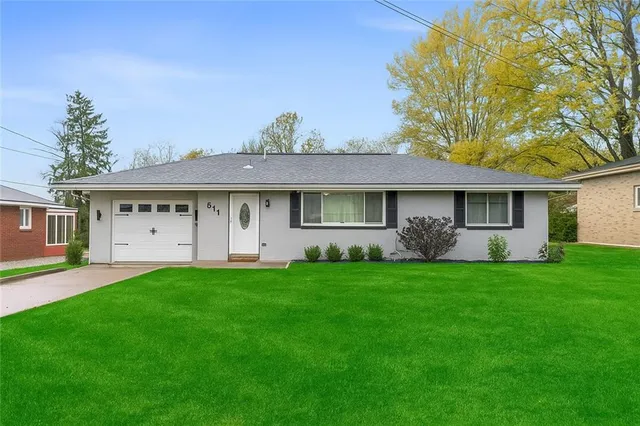 a view of a house with a big yard and large trees