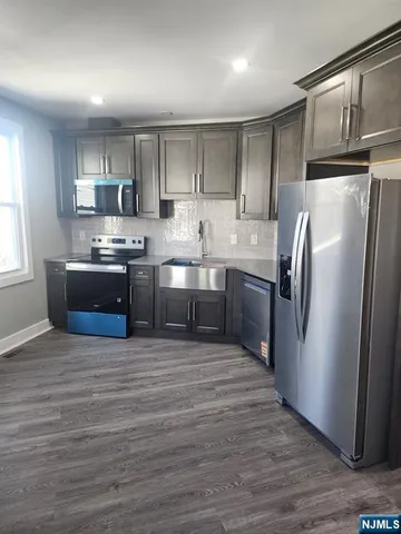 a kitchen with stainless steel appliances granite countertop a refrigerator a stove a sink and a microwave