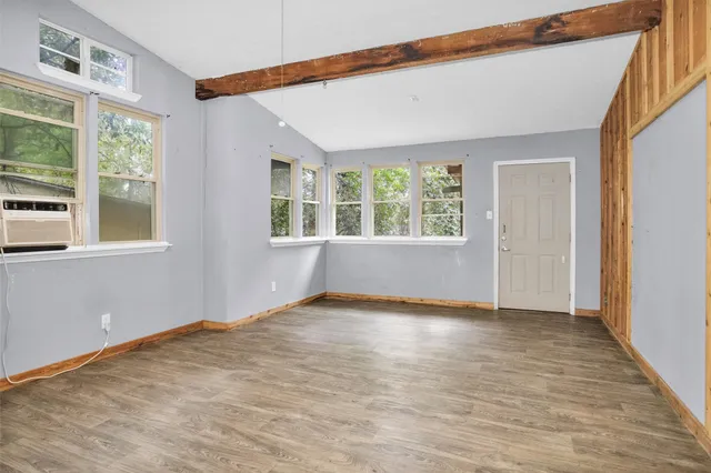 a view of an empty room with a window and wooden floor
