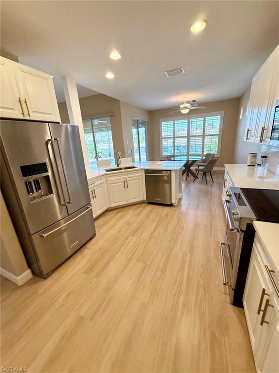 10228 Cobble Hill Road Bonita Springs, FL 34135 - Photo 2 of 31 Kitchen featuring stainless steel appliances, a peninsula, white cabinetry, light wood-type flooring, and recessed lighting