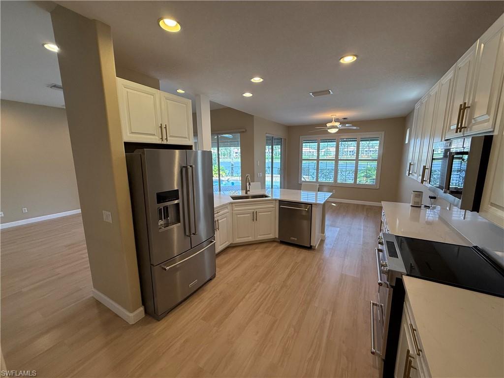 10228 Cobble Hill Road Bonita Springs, FL 34135 - Photo 6 of 31 Kitchen with appliances with stainless steel finishes, white cabinetry, recessed lighting, a peninsula, and light wood finished floors