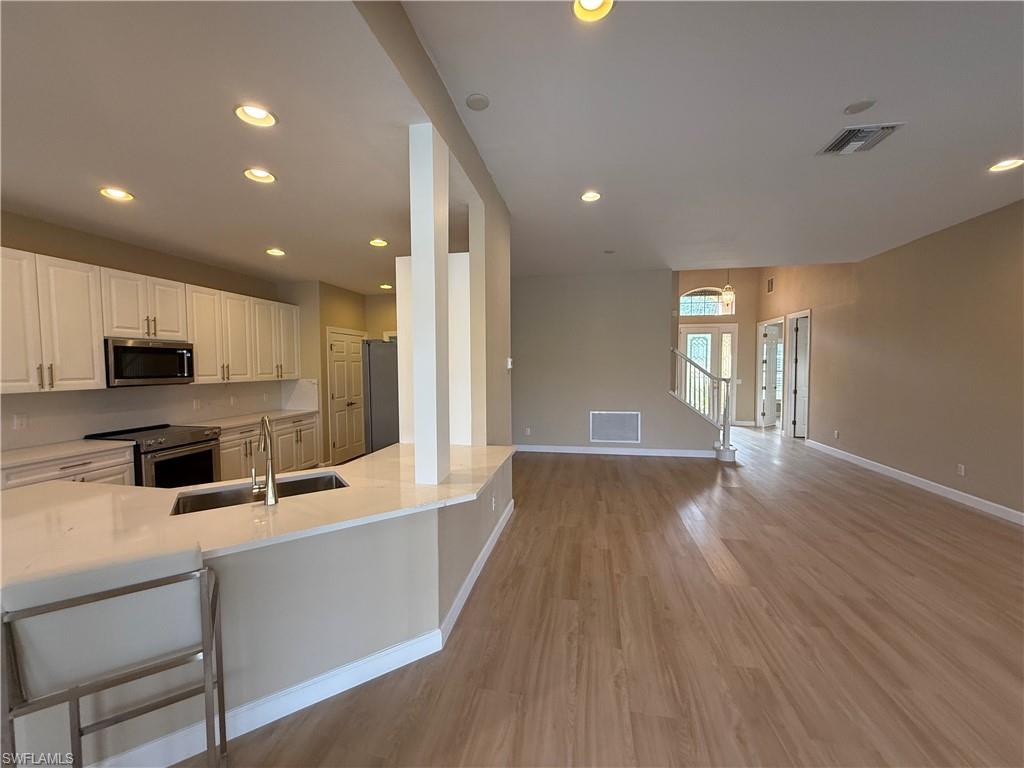 10228 Cobble Hill Road Bonita Springs, FL 34135 - Photo 29 of 31 Kitchen with appliances with stainless steel finishes, open floor plan, a kitchen bar, white cabinets, and recessed lighting