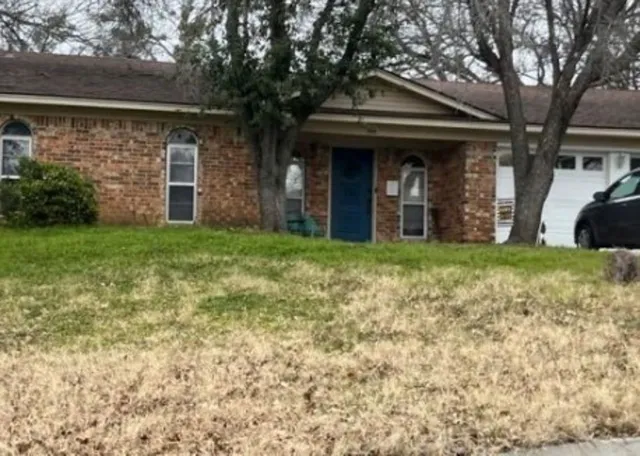 a view of a brick house with a large windows and a big yard