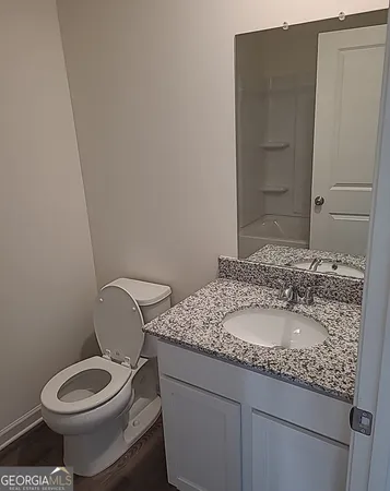 a bathroom with a granite countertop toilet a sink and a mirror