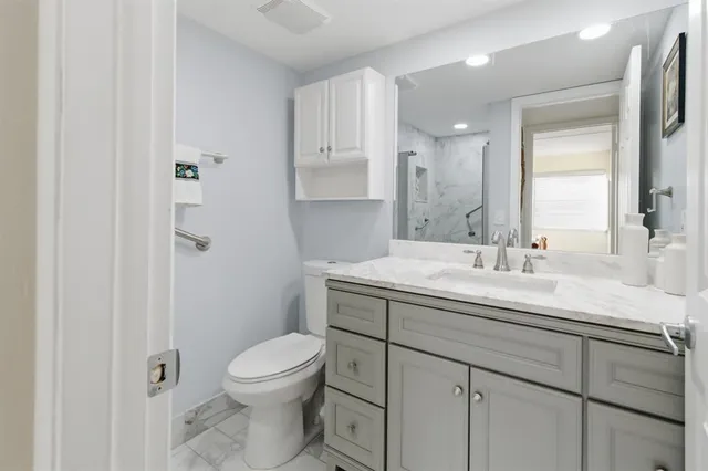 a bathroom with a granite countertop sink a toilet and a mirror