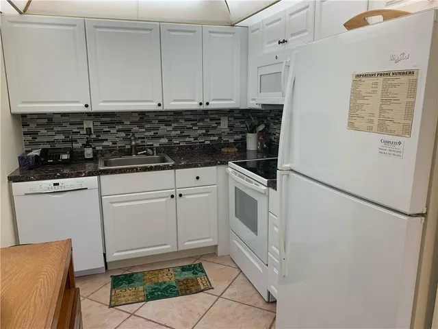 a kitchen with white cabinets and white appliances