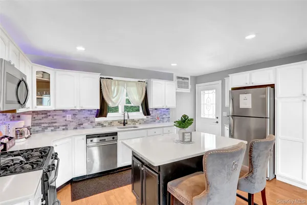 a kitchen with stainless steel appliances granite countertop a kitchen island hardwood floor sink stove dining table and chairs