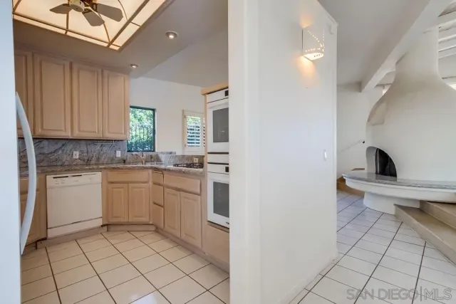 a large white kitchen with a sink and a large window