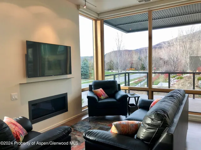 a living room with furniture a flat screen tv and a floor to ceiling window