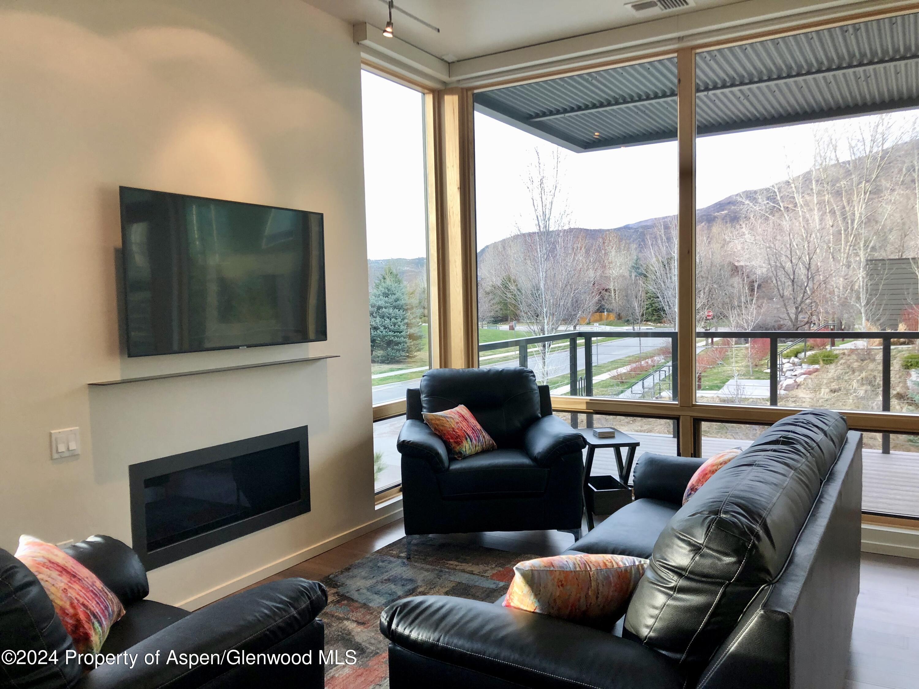200 Evans Road, Unit 102 Basalt, CO 81621 - Photo 2 of 31 a living room with furniture a flat screen tv and a floor to ceiling window