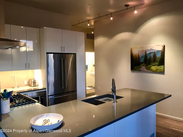 a kitchen with stainless steel appliances granite countertop a sink a refrigerator and a stove