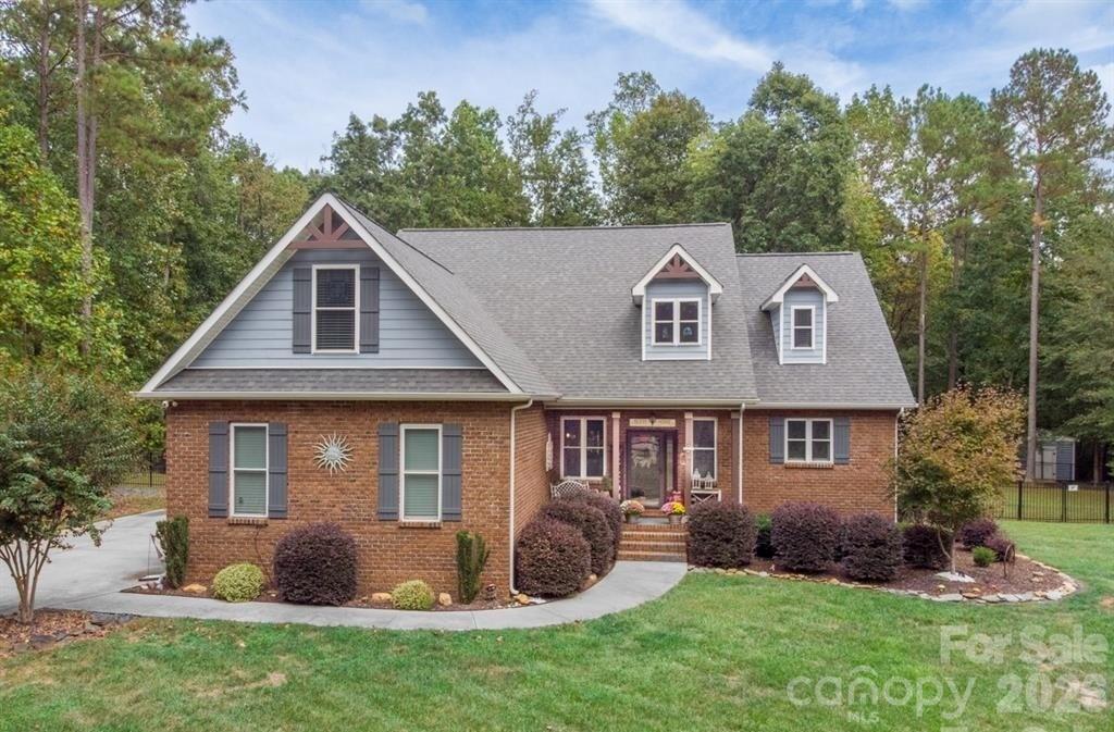 a view of a yard in front of a house with plants and large tree