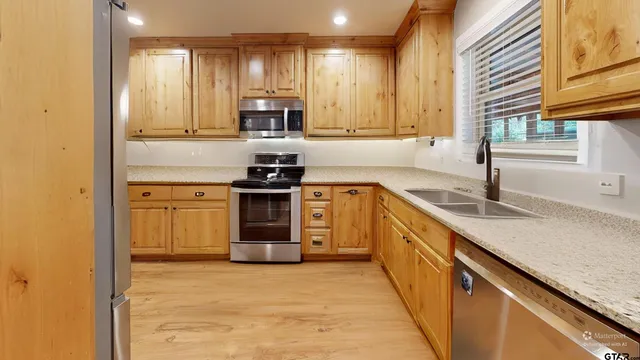a kitchen with stainless steel appliances granite countertop a sink a stove and cabinets