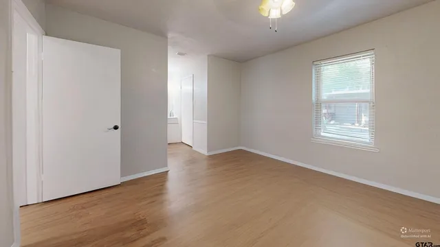 a view of an empty room with window and wooden floor