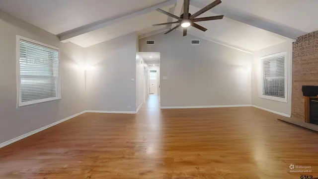 a view of an empty room with window and wooden floor