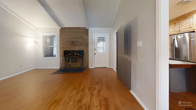 a view of a hallway with wooden floor fireplace and a window