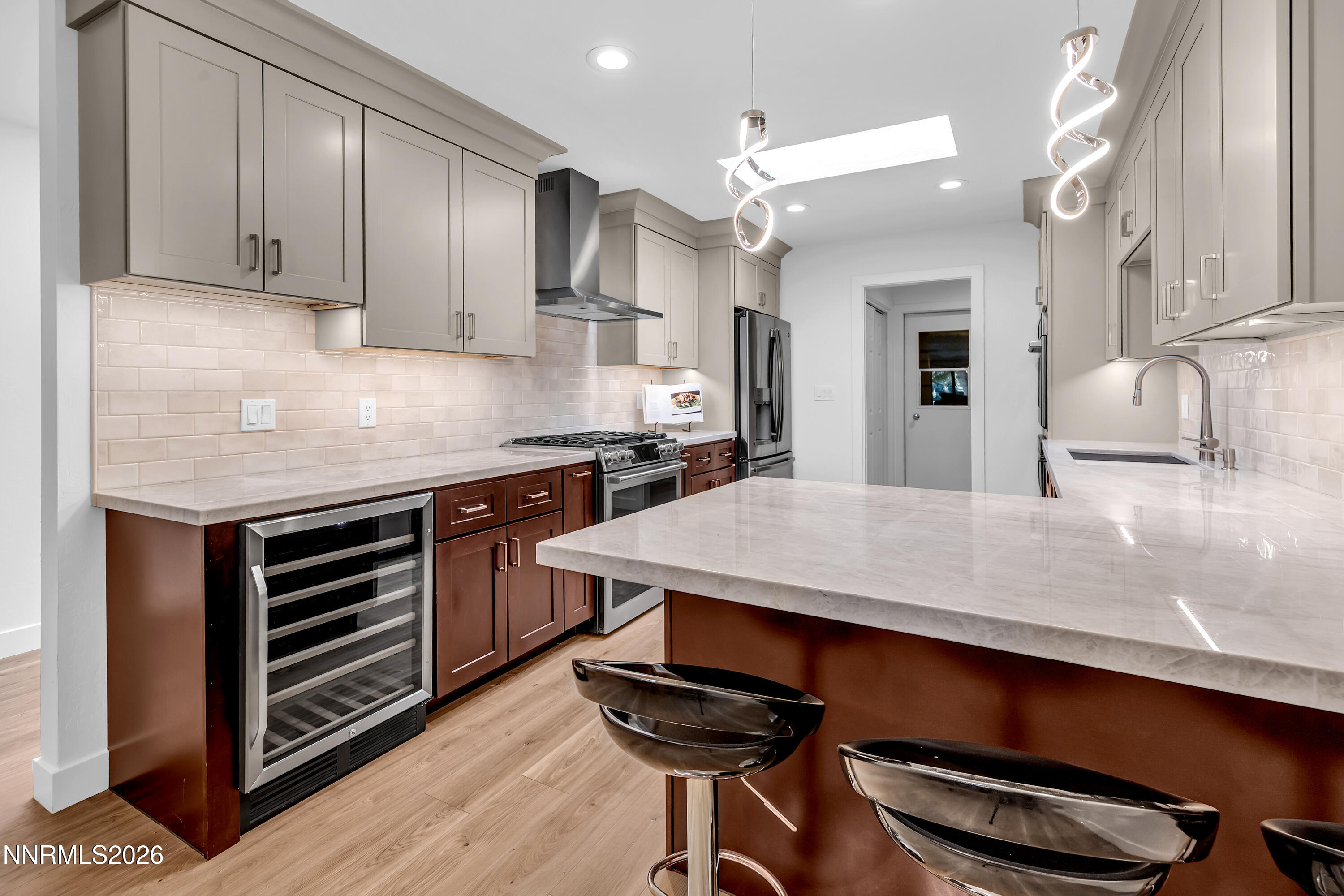 4915 Lakeridge Terrace West Reno, NV 89509 - Photo 5 of 41 a kitchen with stainless steel appliances kitchen island a table chairs in it and wooden floors