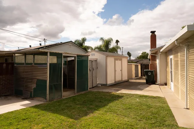 a front view of a house with a yard potted plants and palm trees