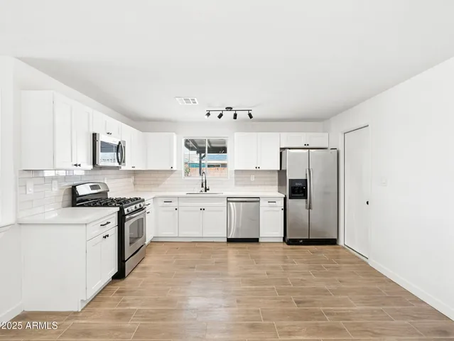 a kitchen with a sink a refrigerator and white cabinets