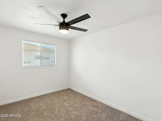 an empty room with a window and a ceiling fan
