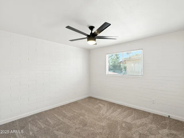 an empty room with a window and a ceiling fan