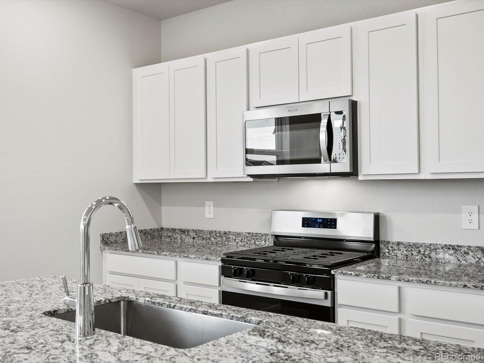4684 Rabbitbrush Street Johnstown, CO 80534 - Photo 18 of 45 a kitchen with stainless steel appliances granite countertop a stove a microwave and cabinets