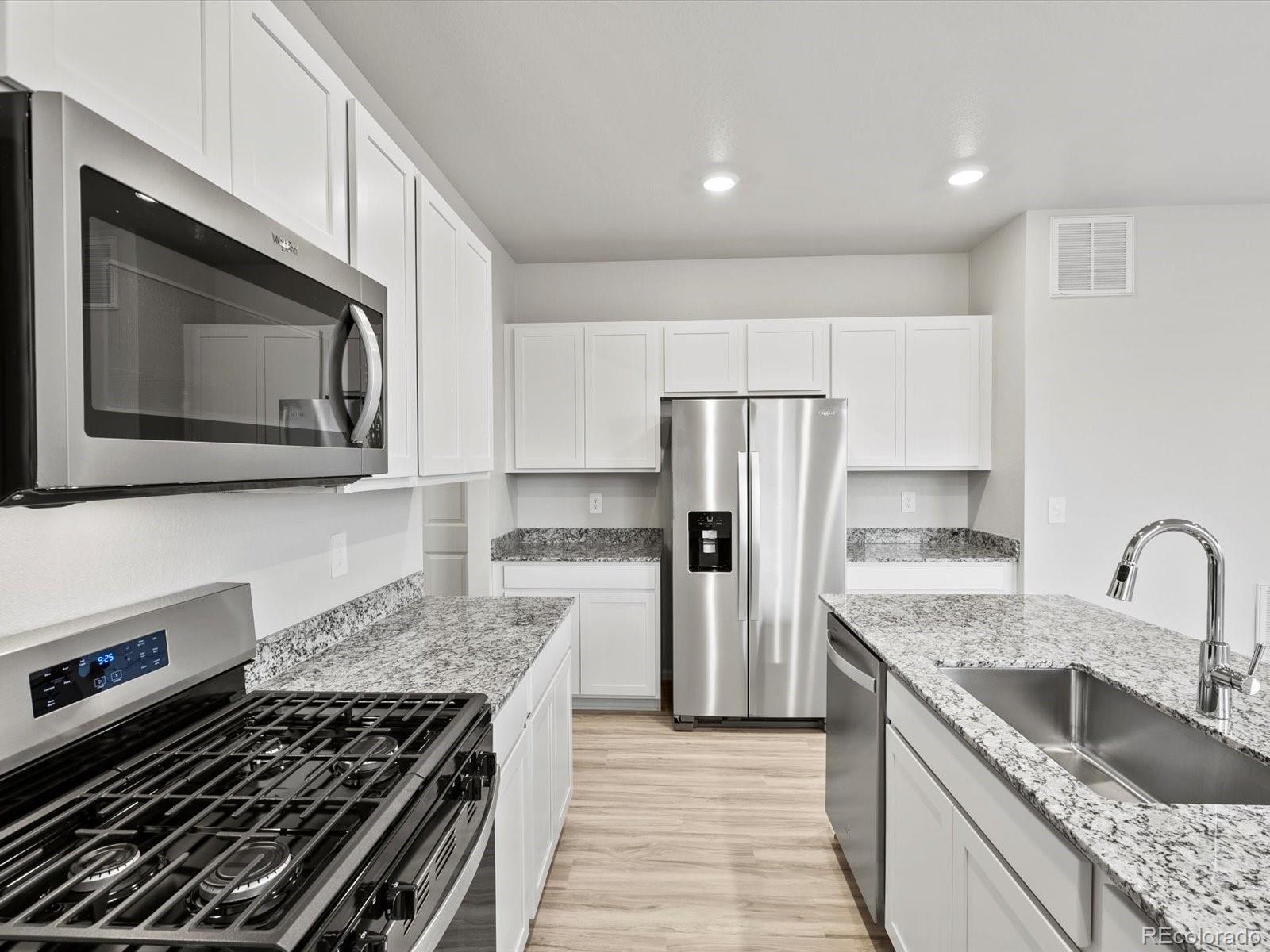 4684 Rabbitbrush Street Johnstown, CO 80534 - Photo 19 of 45 a kitchen with granite countertop a sink stove and refrigerator
