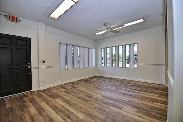 a view of an empty room with a window and wooden floor