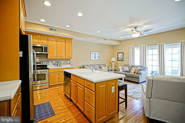 a open kitchen with stainless steel appliances granite countertop a stove top oven a sink dishwasher and white cabinets with wooden floor