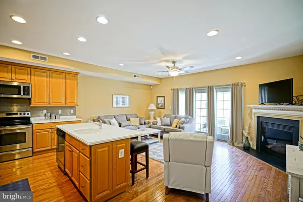 a large kitchen with stainless steel appliances granite countertop a stove top oven a sink dishwasher a dining table and chairs with wooden floor