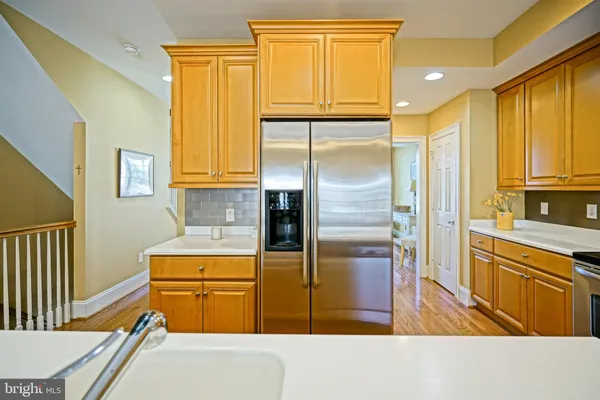 a kitchen with stainless steel appliances granite countertop a refrigerator a stove and white cabinets with wooden floor