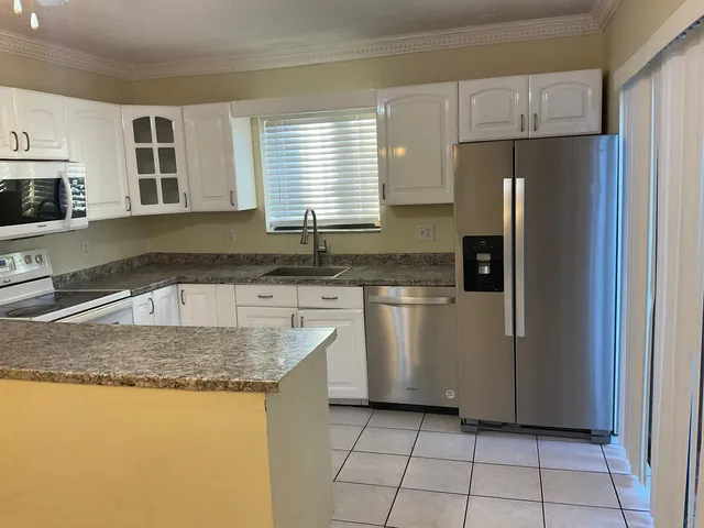 a kitchen with granite countertop a sink stove and refrigerator