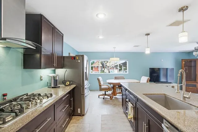 a kitchen with stainless steel appliances kitchen island granite countertop a sink stove and refrigerator