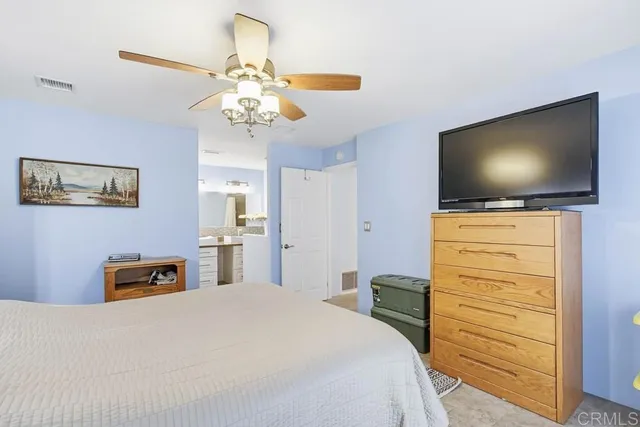 a bedroom with a bed and a flat tv screen on dresser