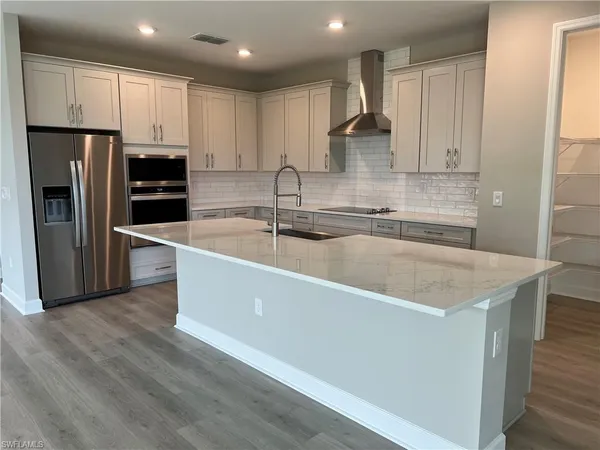 a large kitchen with stainless steel appliances granite countertop a sink a stove and a refrigerator