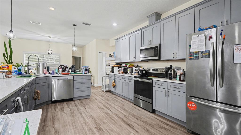 5211 Southwest 103rd Loop Ocala, FL 34476 - Photo 5 of 18 a kitchen with granite countertop a refrigerator stove and sink with wooden floor