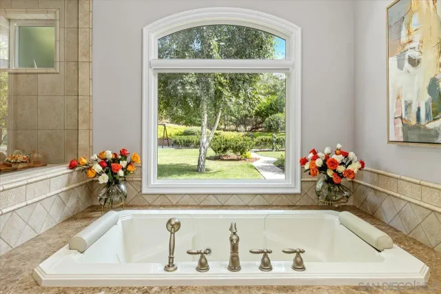 a bathroom with a granite countertop tub sink and mirror